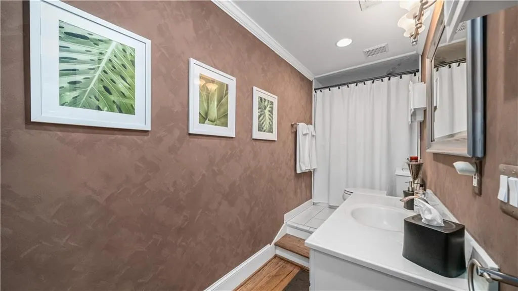 Terrace level bathroom with crown molding and a spacious vanity and a bathtub.