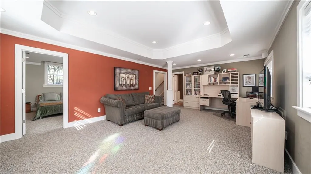 Terrace leve family room featuring a tray ceiling, crown molding, and ornate columns