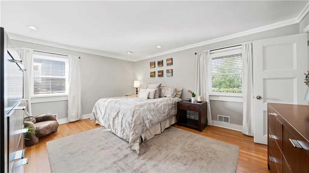 Primary Bedroom with crown molding with light filled room and hardwood floors throughout.
