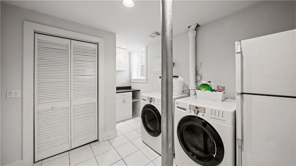 Washroom with light tile floors and washing machine and clothes dryer