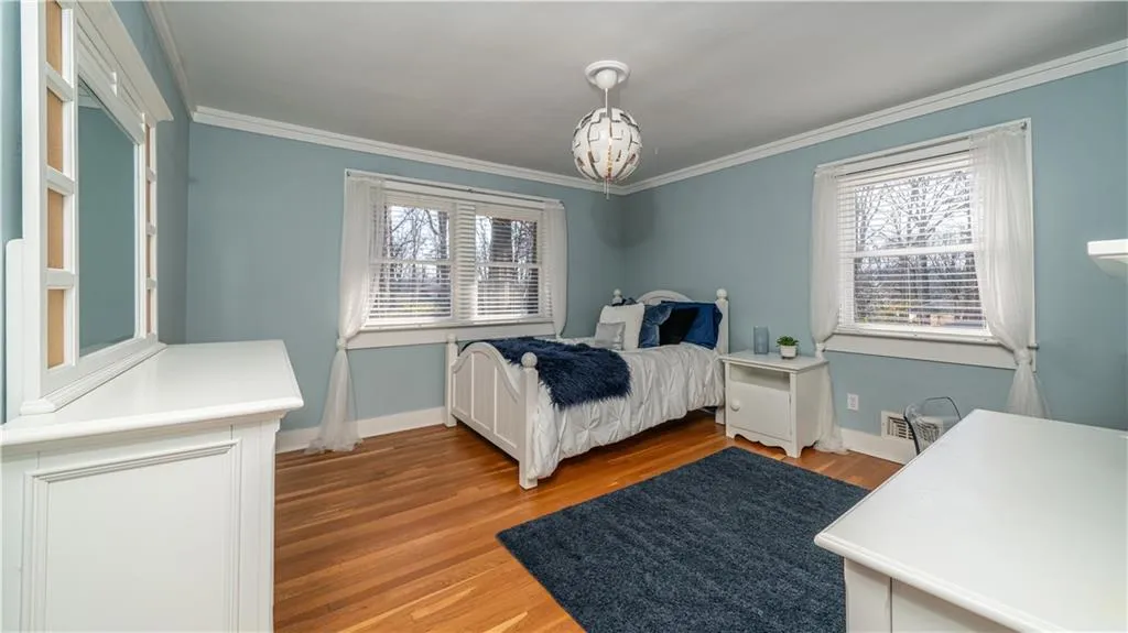 Bedroom with multiple windows, light hardwood / wood-style flooring, and ornamental molding