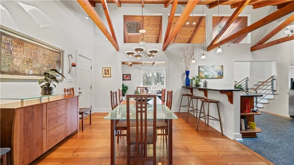 Dining space featuring a chandelier, light hardwood / wood-style flooring, beamed ceiling, and high vaulted ceiling