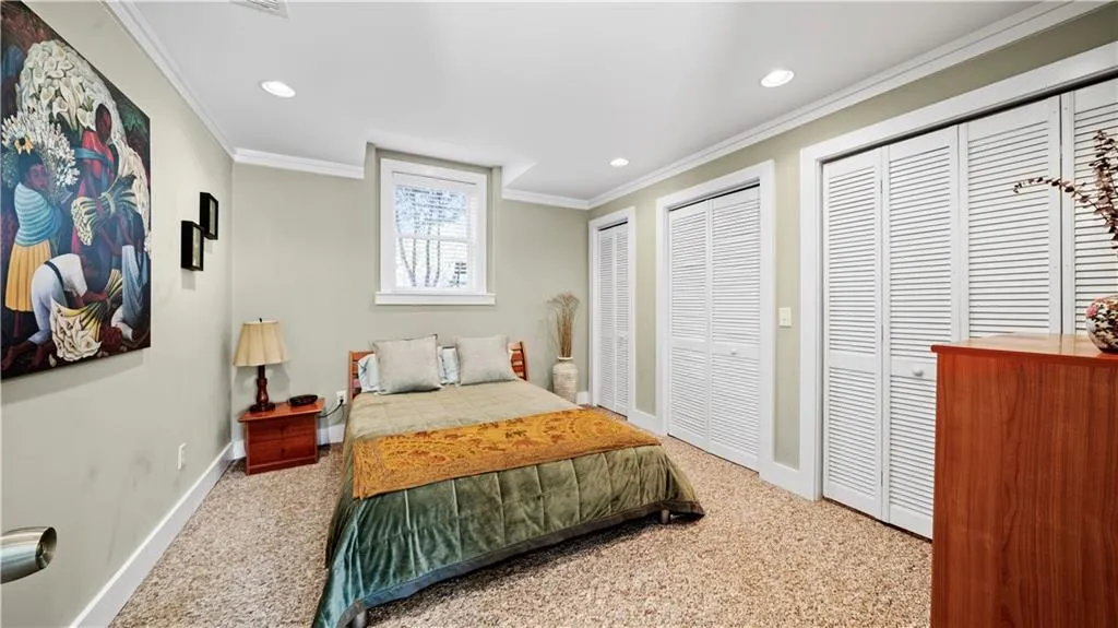 Carpeted bedroom on the terrace level featuring multiple closets and crown molding