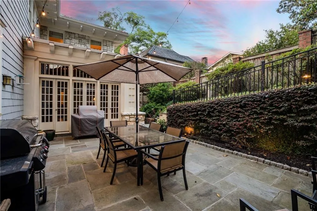 Patio terrace at dusk featuring french doors, outdoor dining space, fence, and a grill