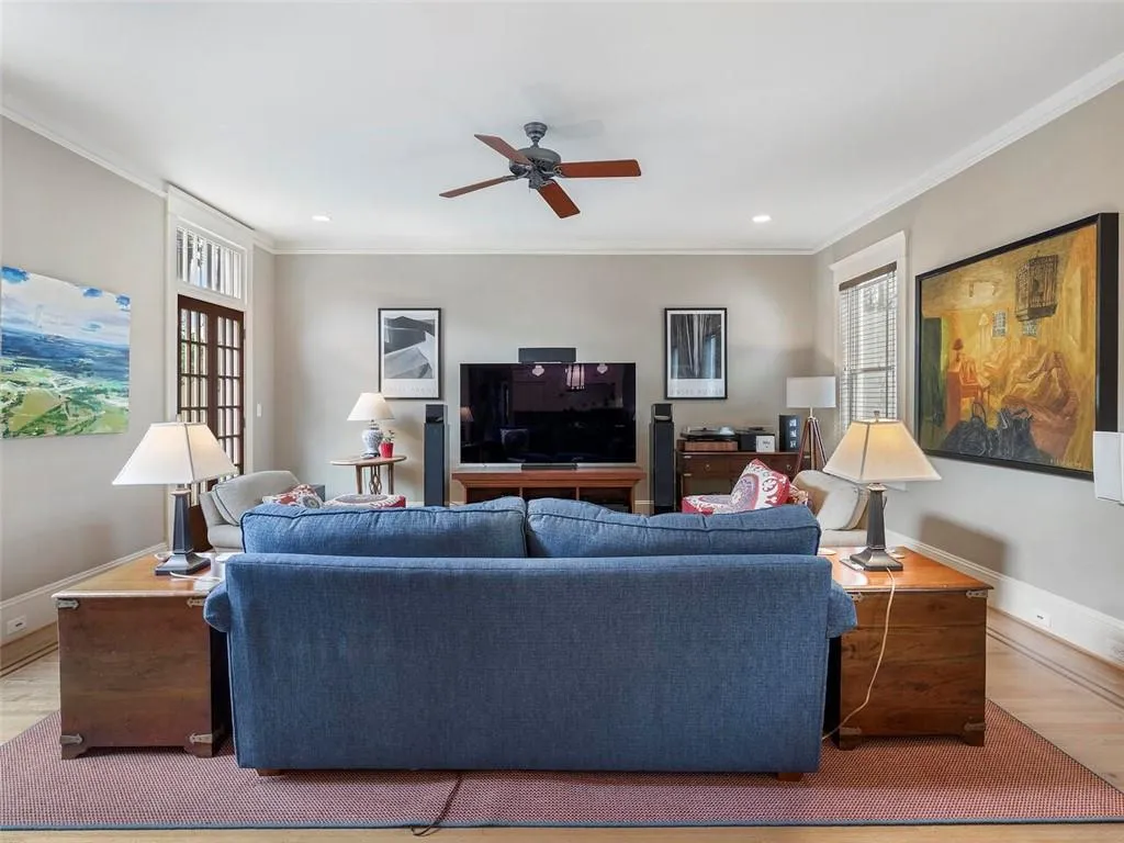 Living area with light wood-type flooring, baseboards, ornamental molding, and a ceiling fan