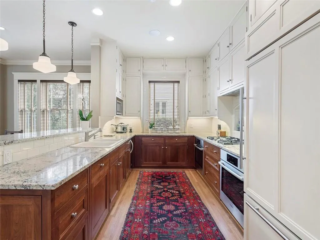 Kitchen with stainless steel appliances, a sink, decorative light fixtures, and light wood-style floors