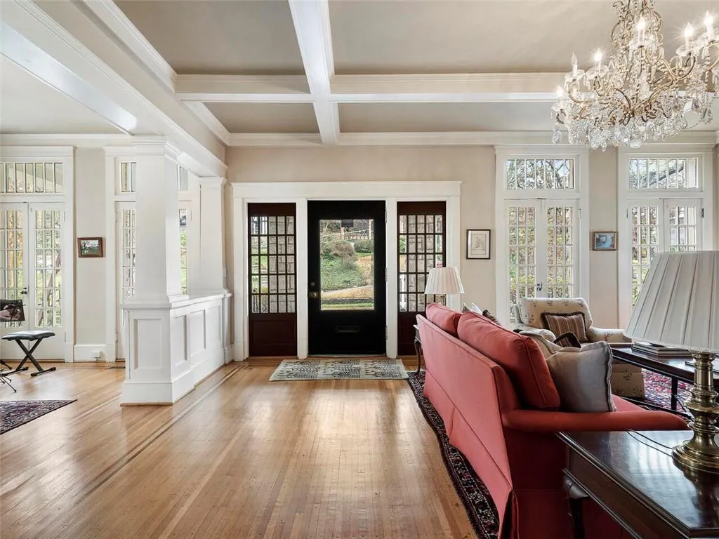 Entrance foyer featuring coffered ceiling, light wood-style floors, french doors, beamed ceiling, and ornate columns