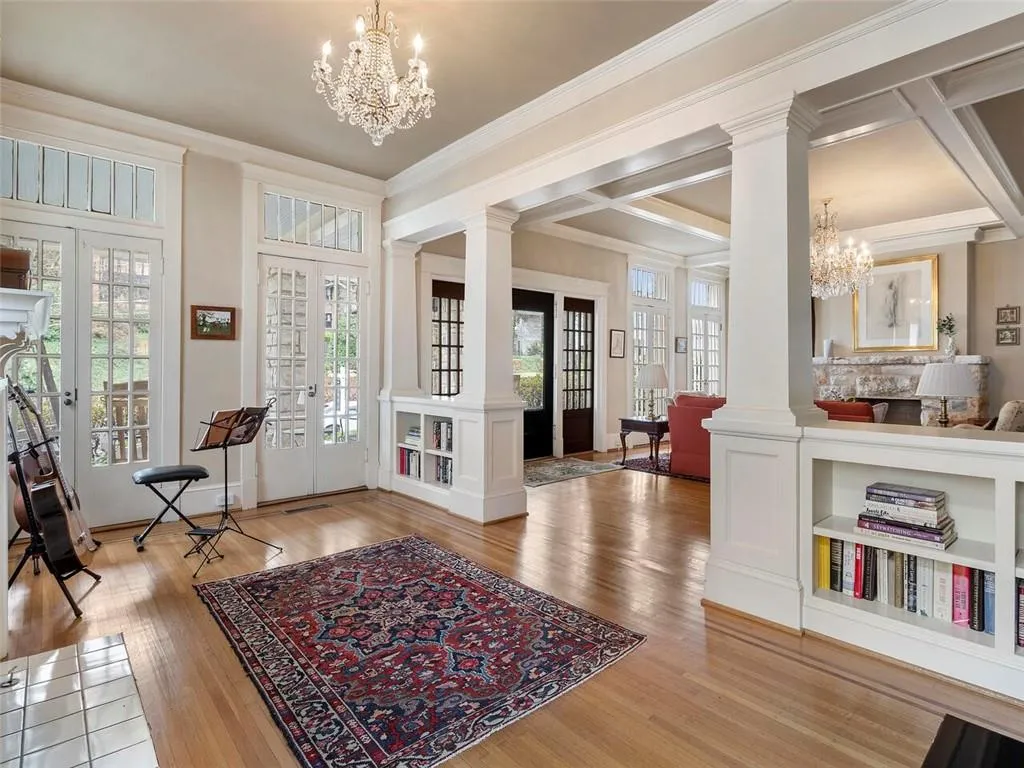 Foyer entrance featuring ornate columns, wood finished floors, an inviting chandelier, and french doors