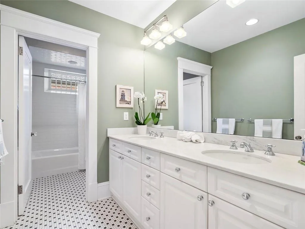 Full bath featuring double vanity, shower / bath combo, a sink, and baseboards