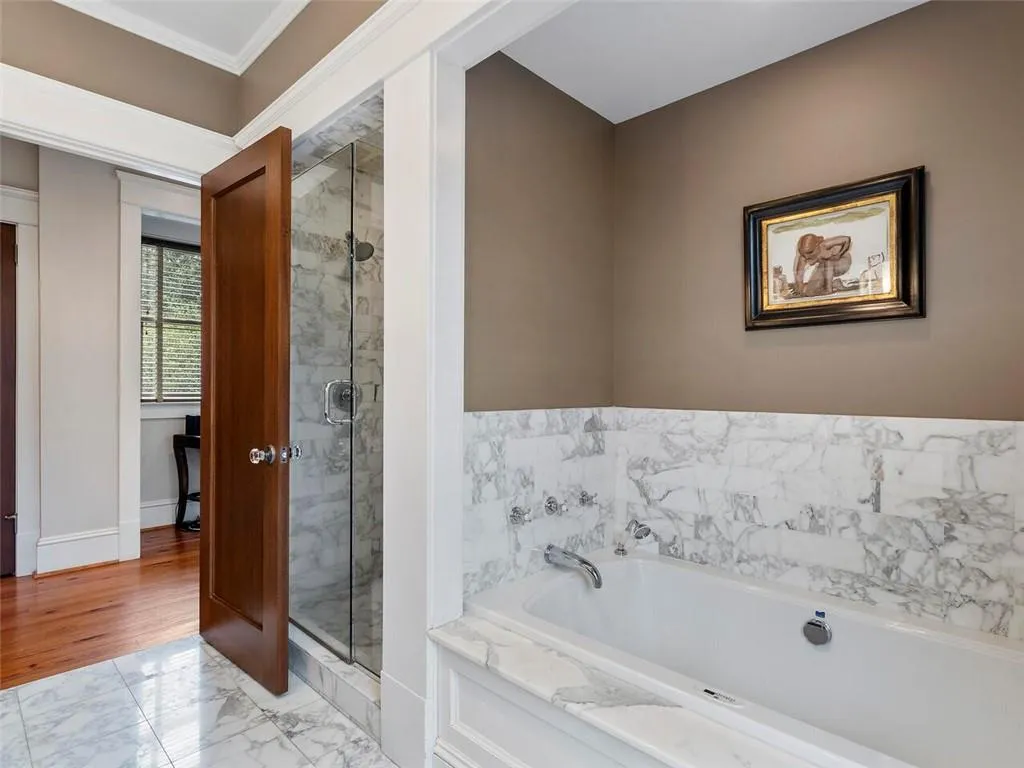Full bath with marble finish floor, a stall shower, a bath, and baseboards