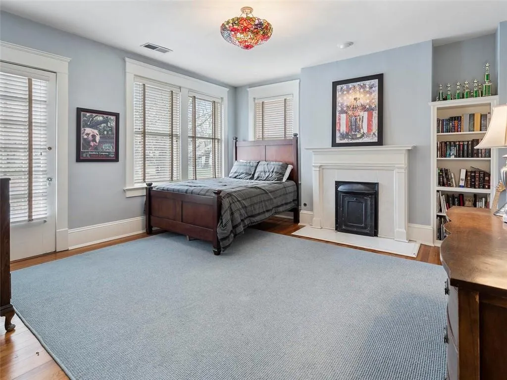 Bedroom featuring light wood-type flooring, multiple windows, visible vents, and a fireplace