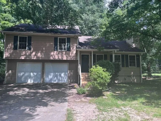 Split-level residence featuring a two-car garage, front entry porch, and traditional shutters