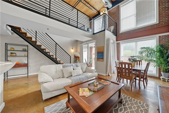 Living room with a high ceiling, finished concrete flooring, and stairway