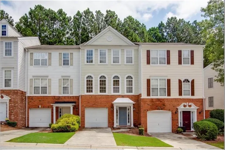 Townhome exterior with brick and siding facade, individual garage, and mature landscaping