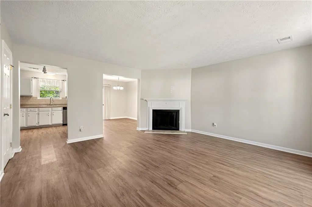 Unfurnished living room with a sink, visible vents, a fireplace with raised hearth, and wood finished floors