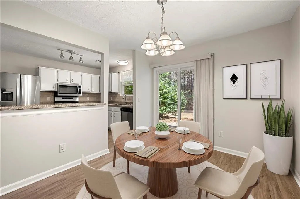 Dining room with a textured ceiling, baseboards, a notable chandelier, and light wood-style floors