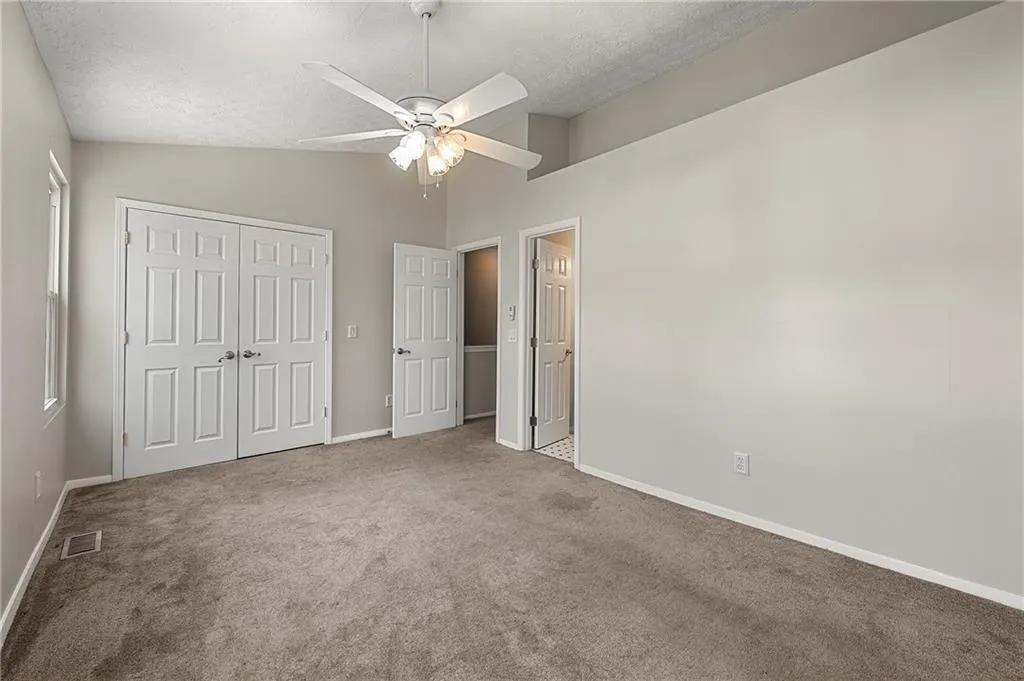 Unfurnished bedroom featuring visible vents, vaulted ceiling, a textured ceiling, carpet floors, and a closet