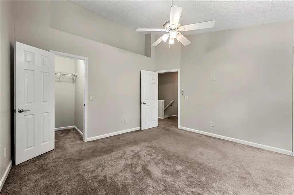 Unfurnished bedroom featuring carpet flooring, a spacious closet, baseboards, and a textured ceiling