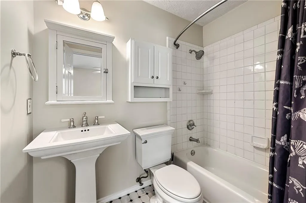 Full bathroom with baseboards, toilet, shower / tub combo with curtain, a textured ceiling, and a sink