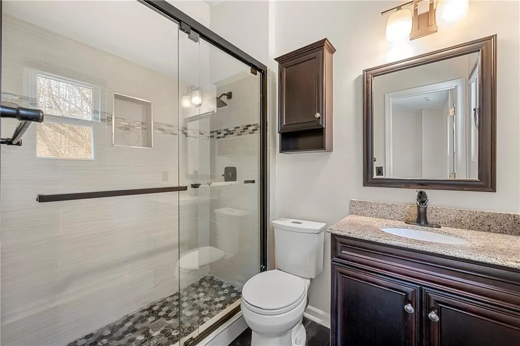 Full bathroom featuring a stall shower, vanity, and toilet