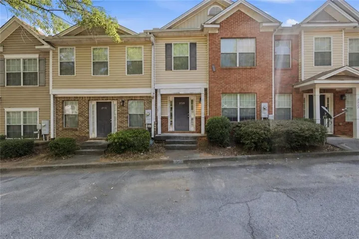 Townhome exterior featuring a combination of brick and siding, multiple windows, and a covered entry
