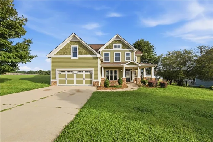 Craftsman-style residence featuring green siding, stone accents, and a covered front porch