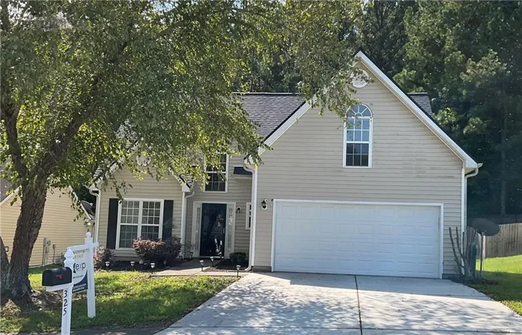 Two-story residence featuring siding exterior, an attached garage, a paved driveway, and a front entry