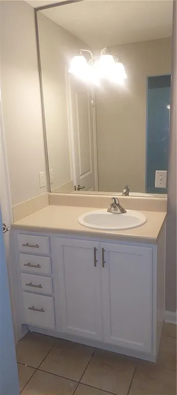 Bathroom with vanity, light tile patterned floors, and a textured ceiling