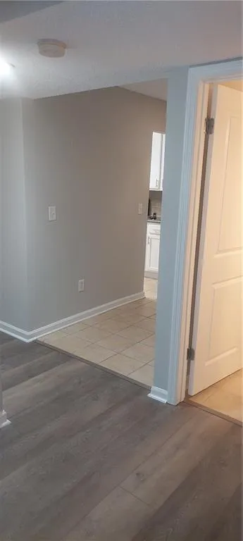Empty room with light wood-style flooring and a smoke detector