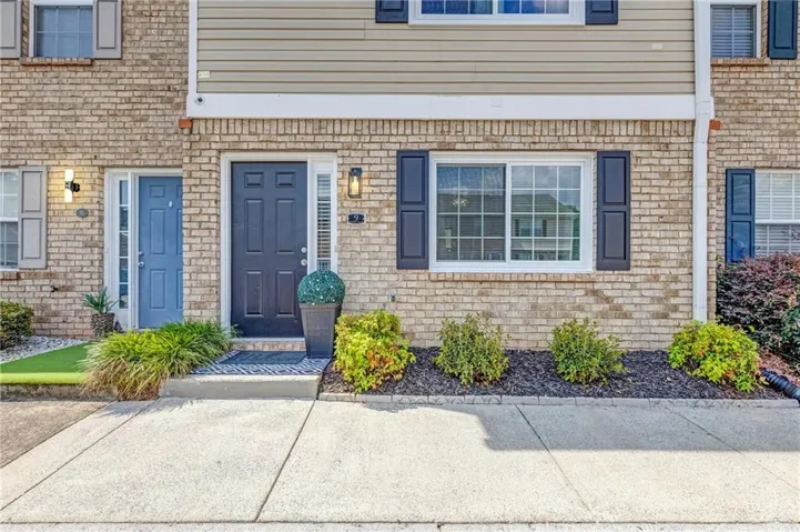 Brick and siding exterior featuring two distinct entry doors, a multi-pane window with dark shutters, and established landscaping
