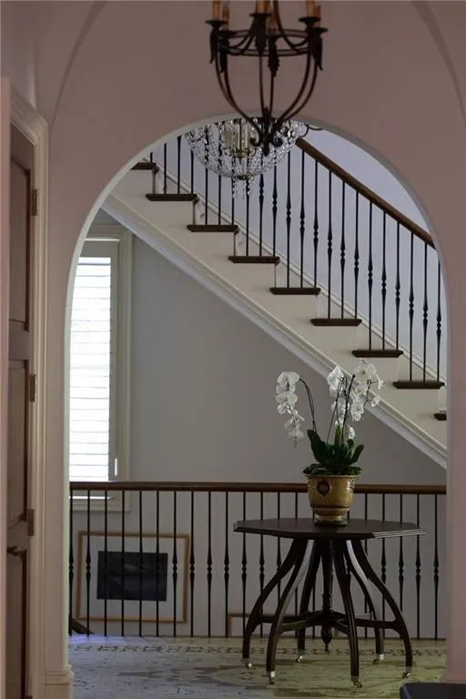 Staircase with marble flooring and a notable chandelier