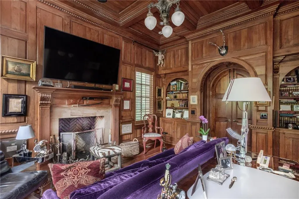 Library with living area with a high end fireplace, wood ceiling, crown molding, wood walls, and mahogany wood flooring