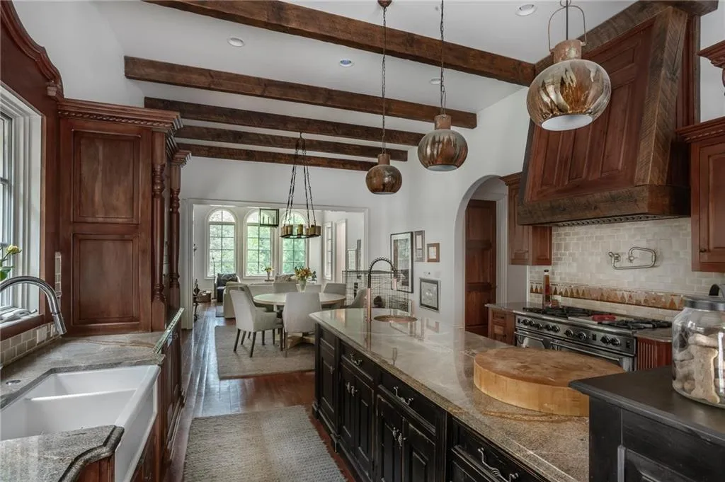 Kitchen featuring high end appliances, light stone countertops, backsplash, a center island with sink, and hardwood / mahogany wood-style flooring