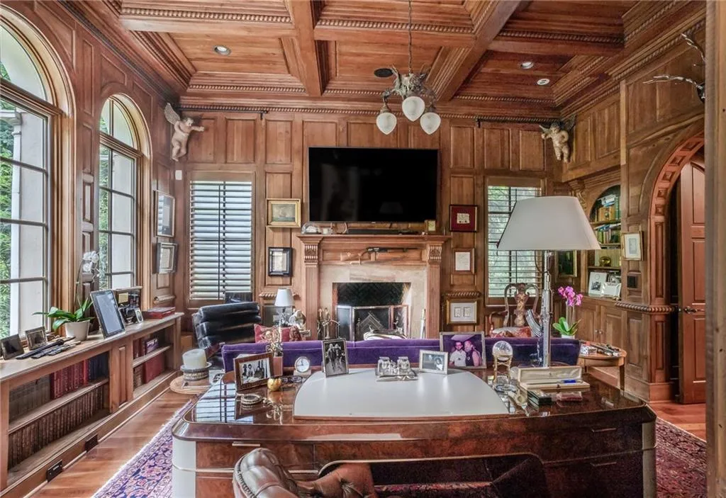 Library with living area with a high end fireplace, wood ceiling, crown molding, wood walls, and mahogany wood flooring