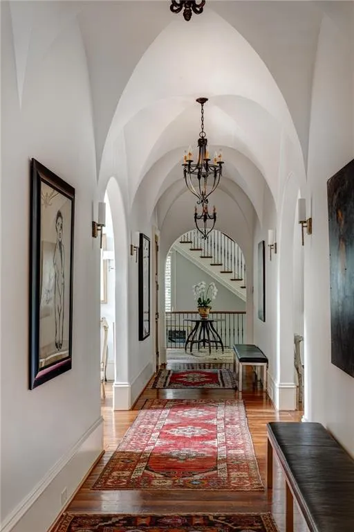 Corridor with hardwood / wood-style flooring and a chandelier