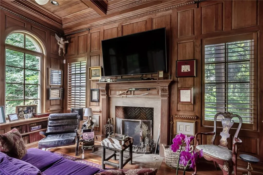 Library with living area with a high end fireplace, wood ceiling, crown molding, wood walls, and mahogany wood flooring