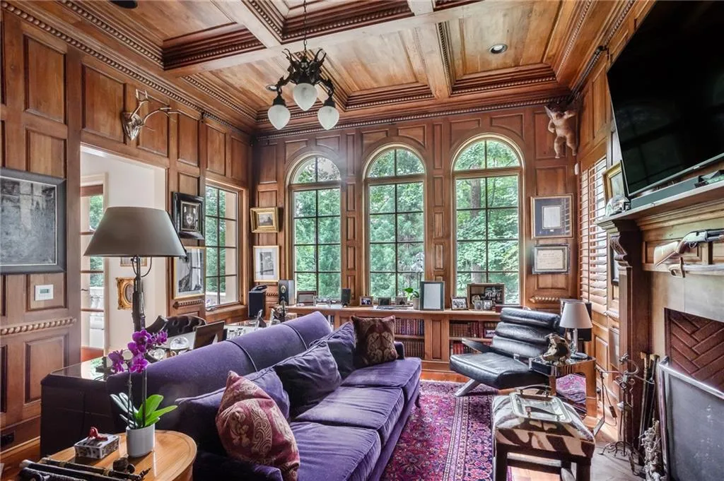 Library with living area with a high end fireplace, wood ceiling, crown molding, wood walls, and mahogany wood flooring