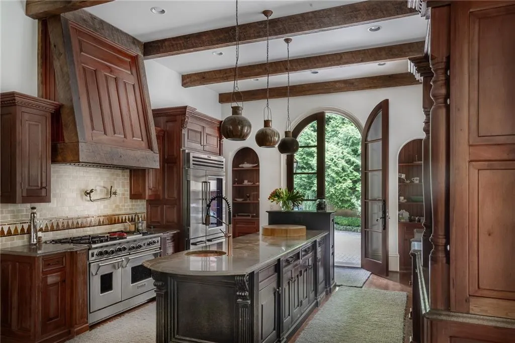 Kitchen featuring high end appliances, light stone countertops, backsplash, a center island with sink, and hardwood / mahogany wood-style flooring