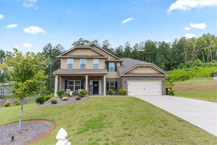 Two-story residence featuring a brick and siding exterior, covered front porch with white columns, two-car garage, and a concrete driveway