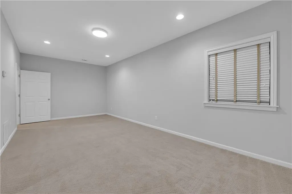 Neutral wall paint, recessed lighting, white trim, paneled door, and carpeting