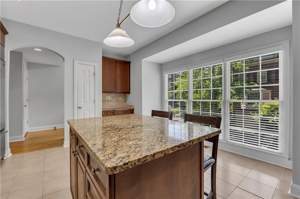 Kitchen island with a polished stone countertop, wood cabinetry, and recessed panel doors