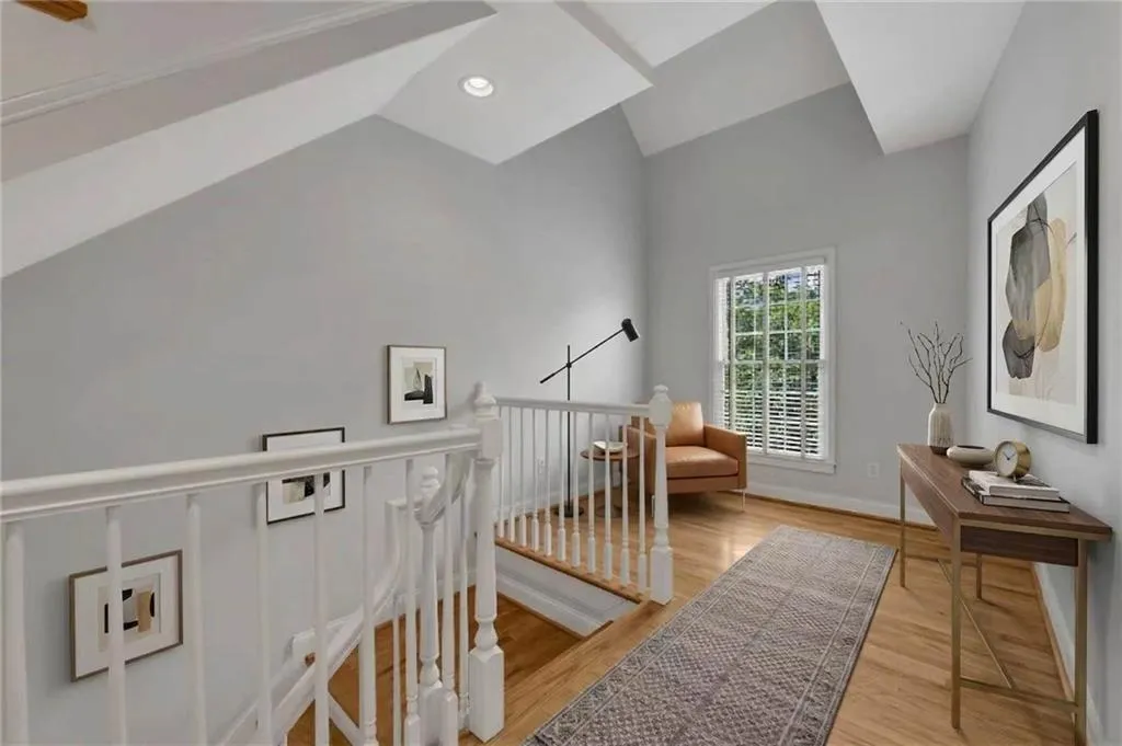 Hardwood flooring, recessed lighting, vaulted ceilings, white baluster railing, and a window with white louvered blinds