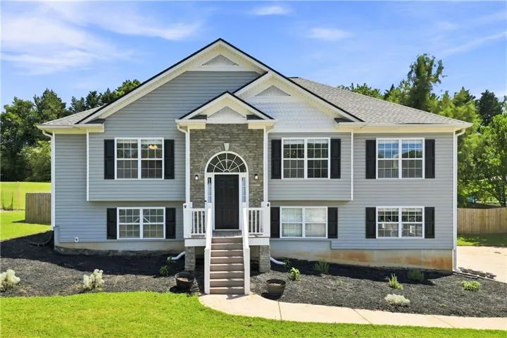 Contemporary exterior with light gray siding, a stone veneer accent, and a prominent arched entryway