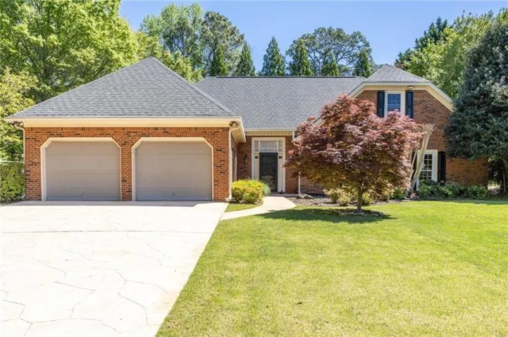 Brick exterior with a gray shingle roof, attached two-car garage, and a concrete driveway