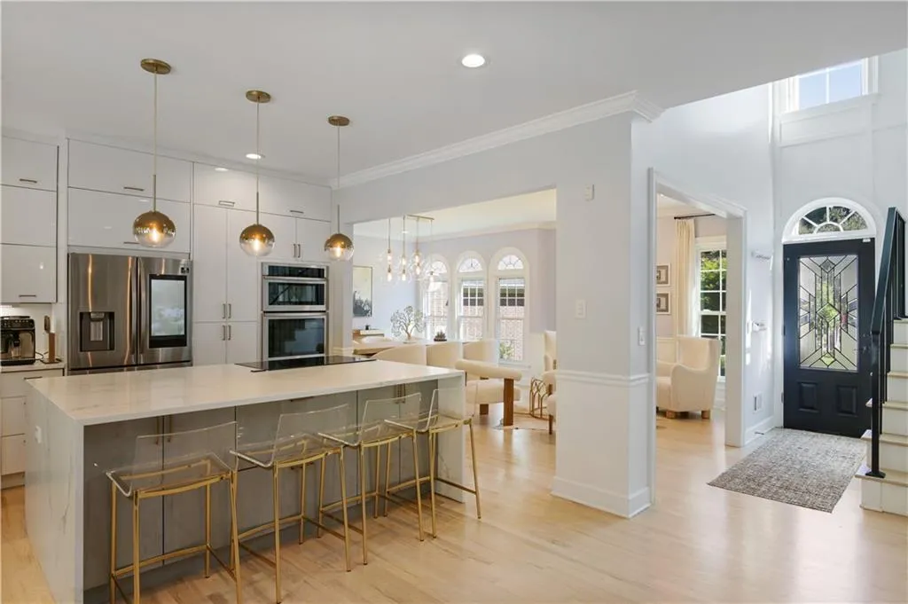Kitchen featuring crown molding, light hardwood / wood-style flooring, appliances with stainless steel finishes, a large island, and pendant lighting