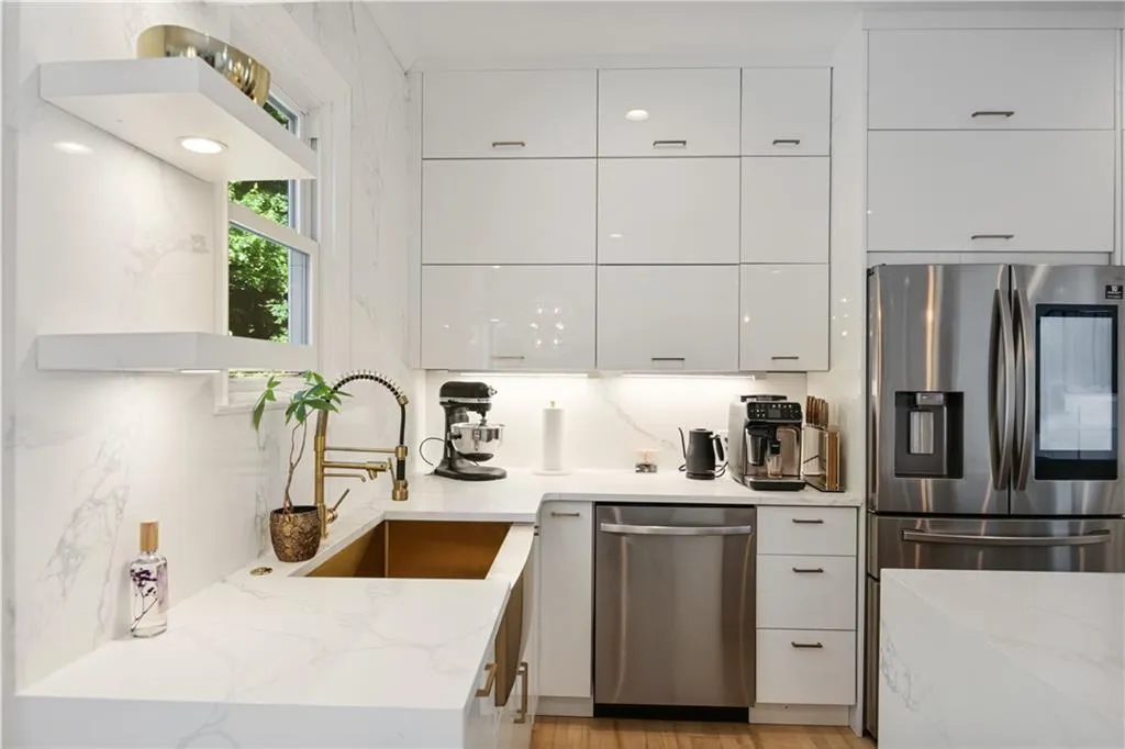 Kitchen featuring light stone counters, white cabinetry, light wood-type flooring, appliances with stainless steel finishes, and sink