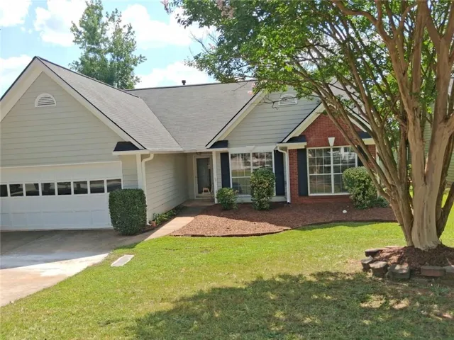 Attached garage, brick facade, shingle roof, landscaped front yard, mature tree