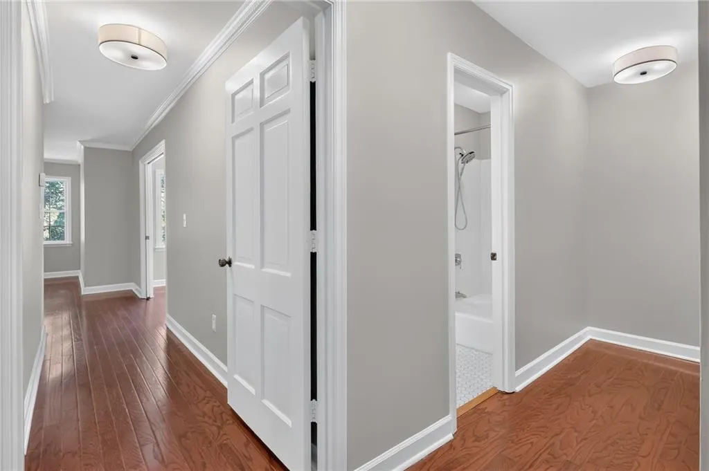 Hallway featuring wood-finish flooring, light gray walls, white trim, and flush-mount ceiling fixtures