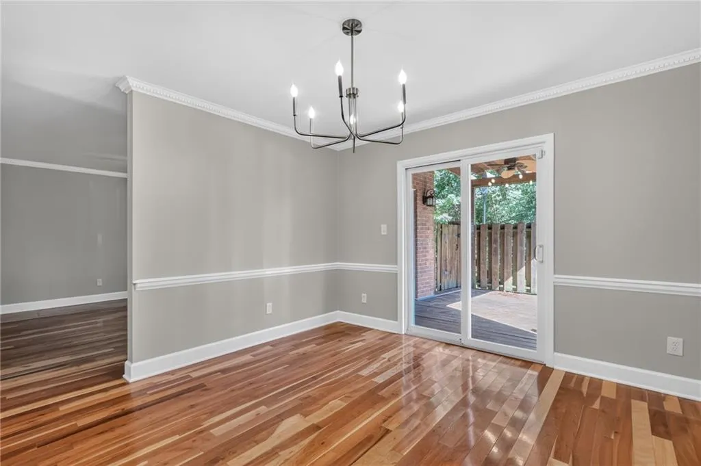 Hardwood flooring, crown molding, chair rail molding, modern chandelier, and sliding glass door