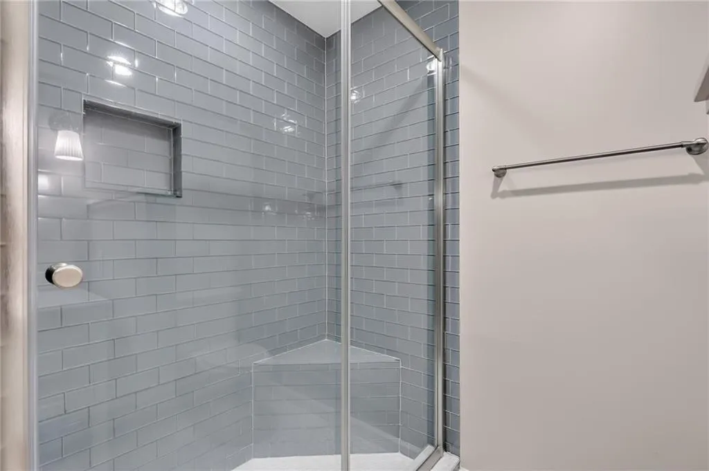 Glass-enclosed shower with subway tile walls, integrated shower niche, and corner bench